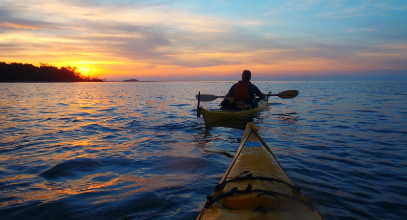 two kayaks are paddled into the sunset on an outward bound veterans expedition 